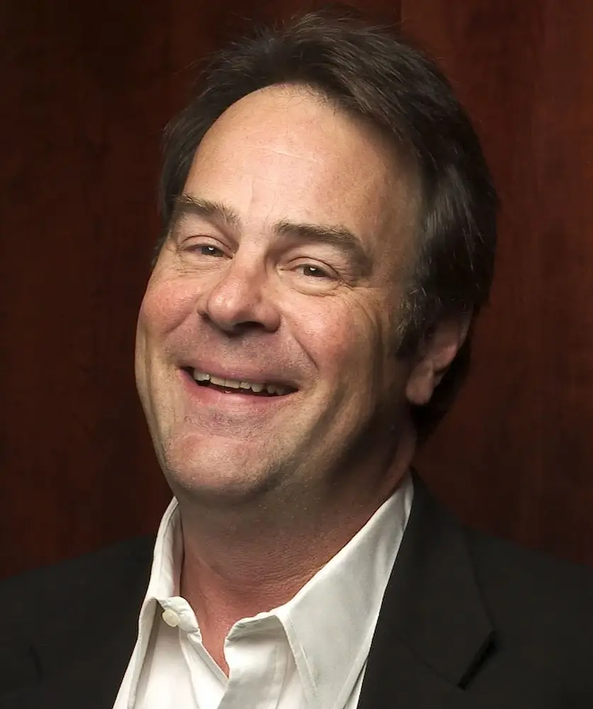 Ator Dan Aykroyd sorrindo para uma fotografia.