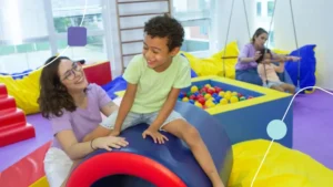 Crianças com autismo em sala sensorial com duas terapeutas praticando a atenção compartilhada.