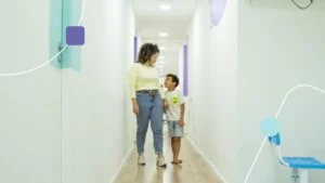 Mãe andando de mãos dadas com seu filho em uma clínica de autismo em São Paulo.