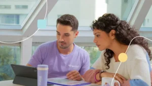 Terapeuta da Genial Care sentado com mãe explicando qual o papel da família na terapia de crianças autistas.