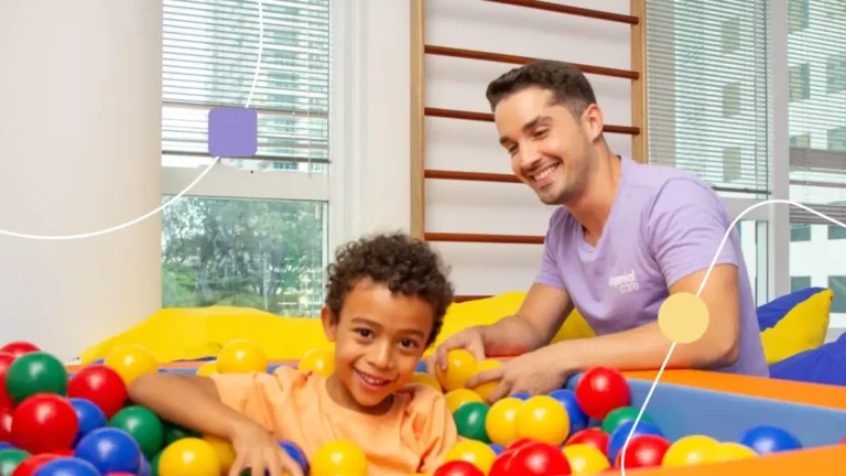 terapia personalizada em sala sensorial: terapeuta brincando com criança em uma piscina de bolinhas,