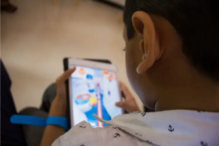 Menino com tablet em viagem com criança autista e sua família