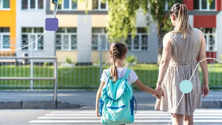 Mães com sua filha no dia das volta às aulas. Elas caminham pela rua de mãos dadas.