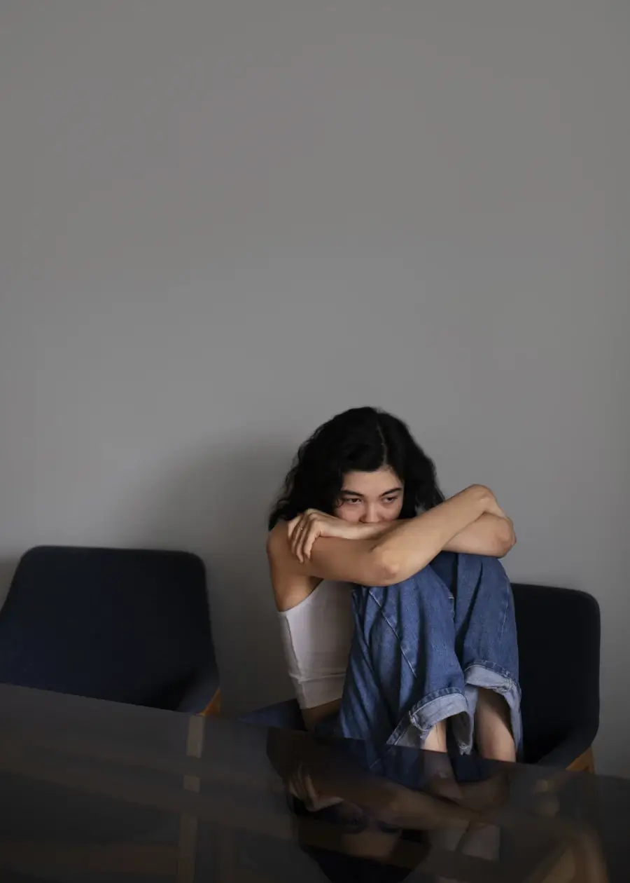 Depressão em adolescentes autistas: menina em posição contraída, triste em sua casa