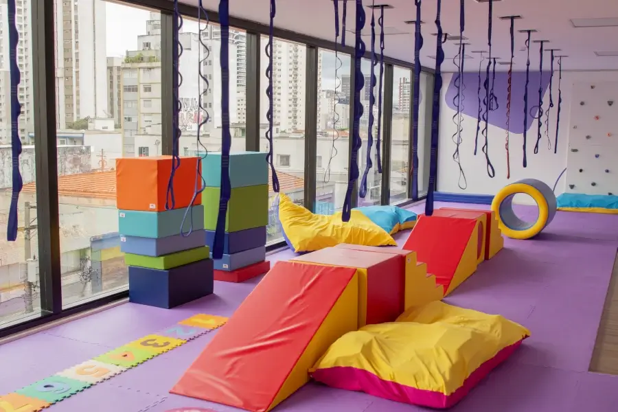 Sala sensorial da Casa Genial com balanços, plataformas, rampas e parede de escalada