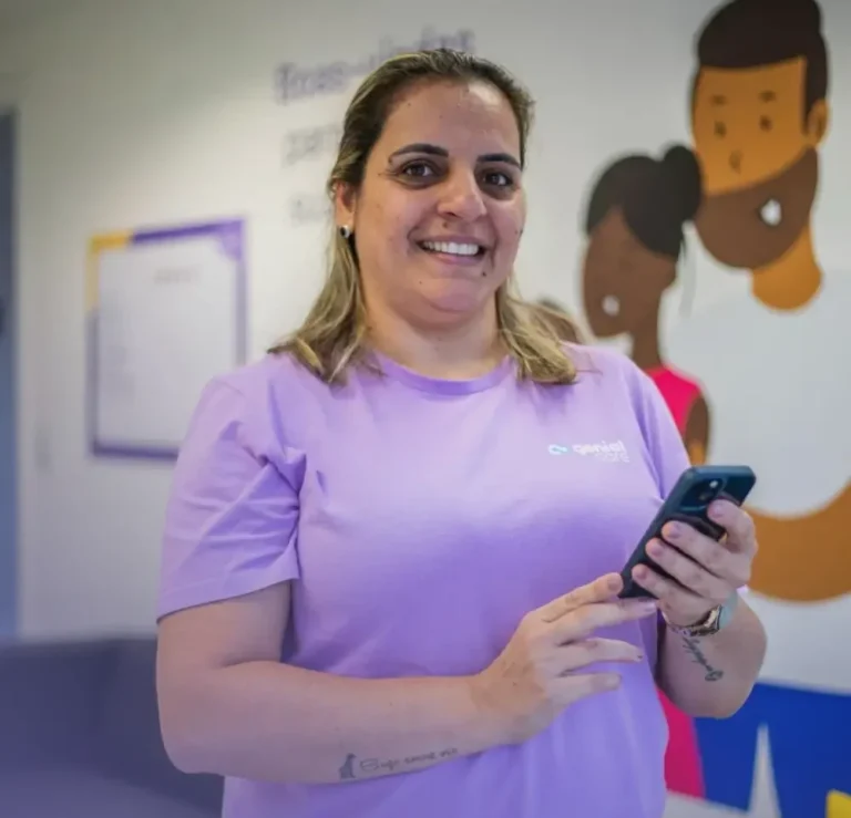 Terapeuta Genial sorrindo com o celular na recepção de uma Casa Genial
