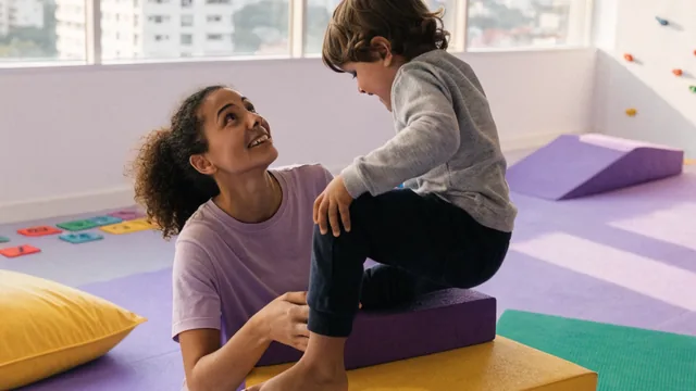 Terapeuta acompanhando uma criança na sala sensorial da Casa Genial